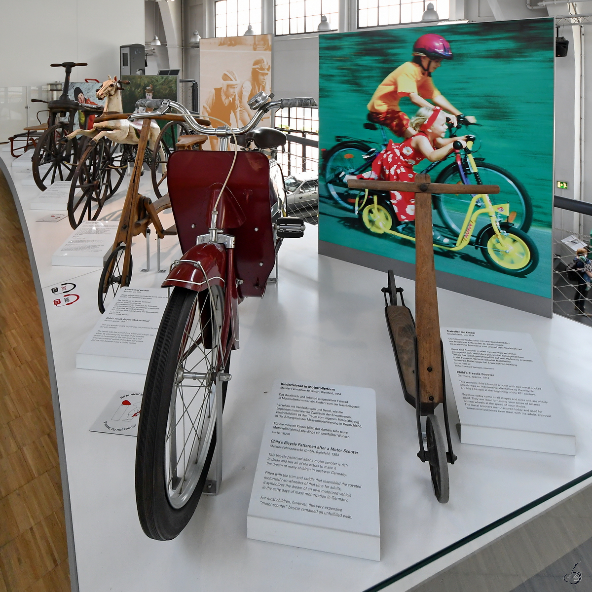 Ein Tretroller für Kinder von 1914, ein Kinderfahrrad in Motorrollerform aus dem Jahr 1954 sowie weiteres Spielzeug ist im Verkehrszentrum des Deutschen Museums in München ausgestellt. (August 2020)