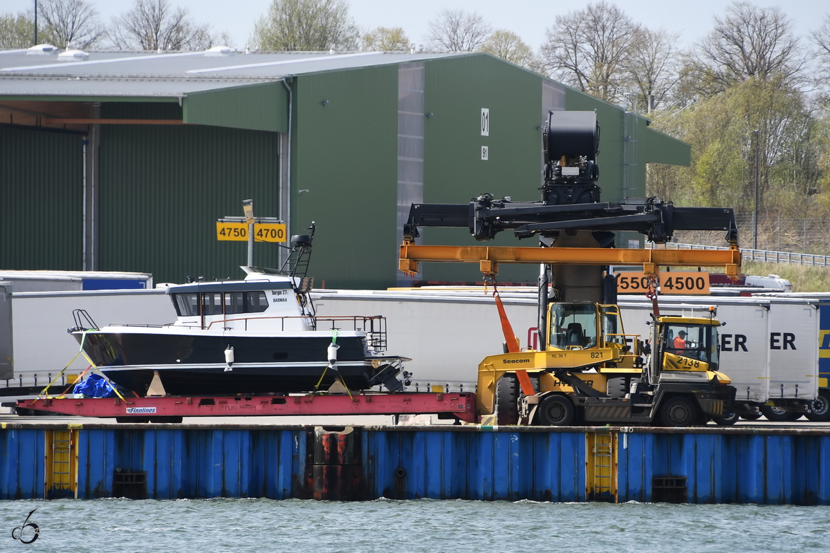 Eine Terminalzugmaschine von Terberg zieht ein gerade angeliefertes Motorboot an den Hafenkai. (Travemünde, Mai 2023)