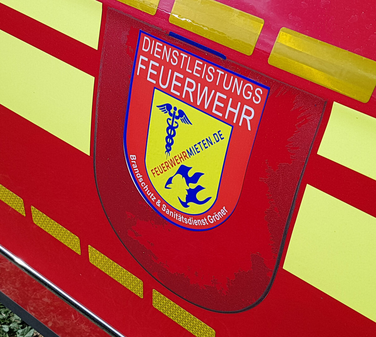 =Emblem der Dienstleistungsfeuerwehr GRÖNER, gesehen auf dem Parkplatz der RettMobil 2022 in Fulda