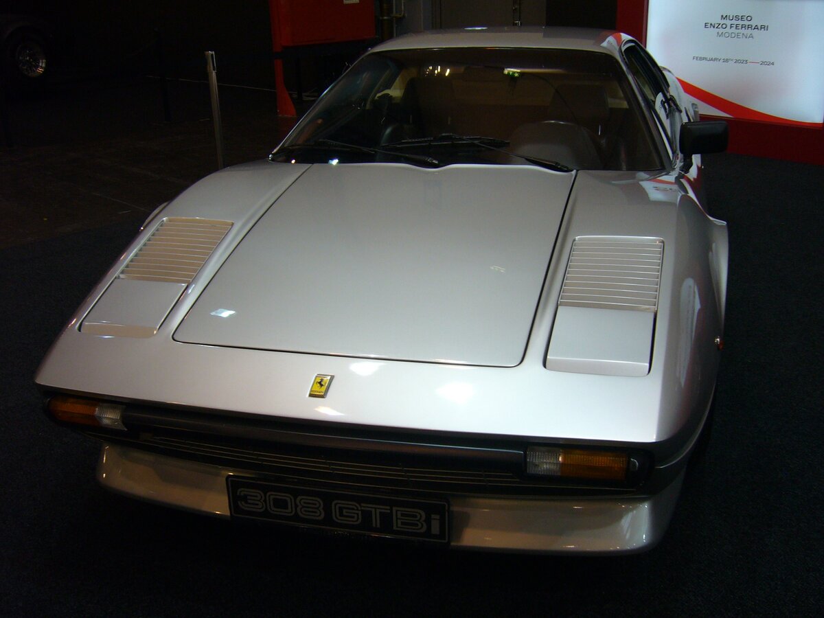Ferrari 308GTBi im Farbton grigio chiaro metallizzato. Das Modell 308GTB kam 1976 auf den Markt. Basierend auf dem Chassis des  Dino  wurde das Modell anfangs aus GFK, später in Blechbauweise produziert. Die  308  steht übrigens für 3.0 Liter Hubraum und die 8 Zylinder. Ab 1980 war das Modell aufgrund strengerer Abgasbestimmungen nur noch als 308GTBi mit Benzineinspritzung lieferbar. Der als Mittelmotor verbaute V8-Motor hat einen Hubraum von 2927 cm³ und leistet in der GTBi Version 214 PS. Techno Classica Essen am 13.04.2023.