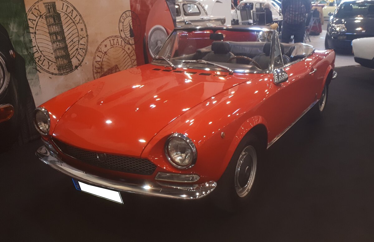 Fiat 124 1600 Sport Spider. Der 124 Sport Spider wurde im November 1966 auf dem Turiner Auto-Salon vorgestellt. Für das Design der Karosserie zeigte sich Sergio Pininfarina verantwortlich. Bis 1972 wurde dieses Cabriolet fast unverändert produziert. Angetrieben wird der Wagen von einem Vierzylinderreihenmotor, der aus einem Hubraum von 1608 cm³ 112 PS leistet. Die Höchstgeschwindigkeit gab Fiat mit 180 km/h an. Der gezeigte  Sport Spider  wurde 1971 erstmalig zugelassen und dürfte im damaligen Farbton rosso ciliega (kirschrot) lackiert sein. Retro Classics in Essen am 09.04.2026. Retro Classics in Essen am 09.04.2026.