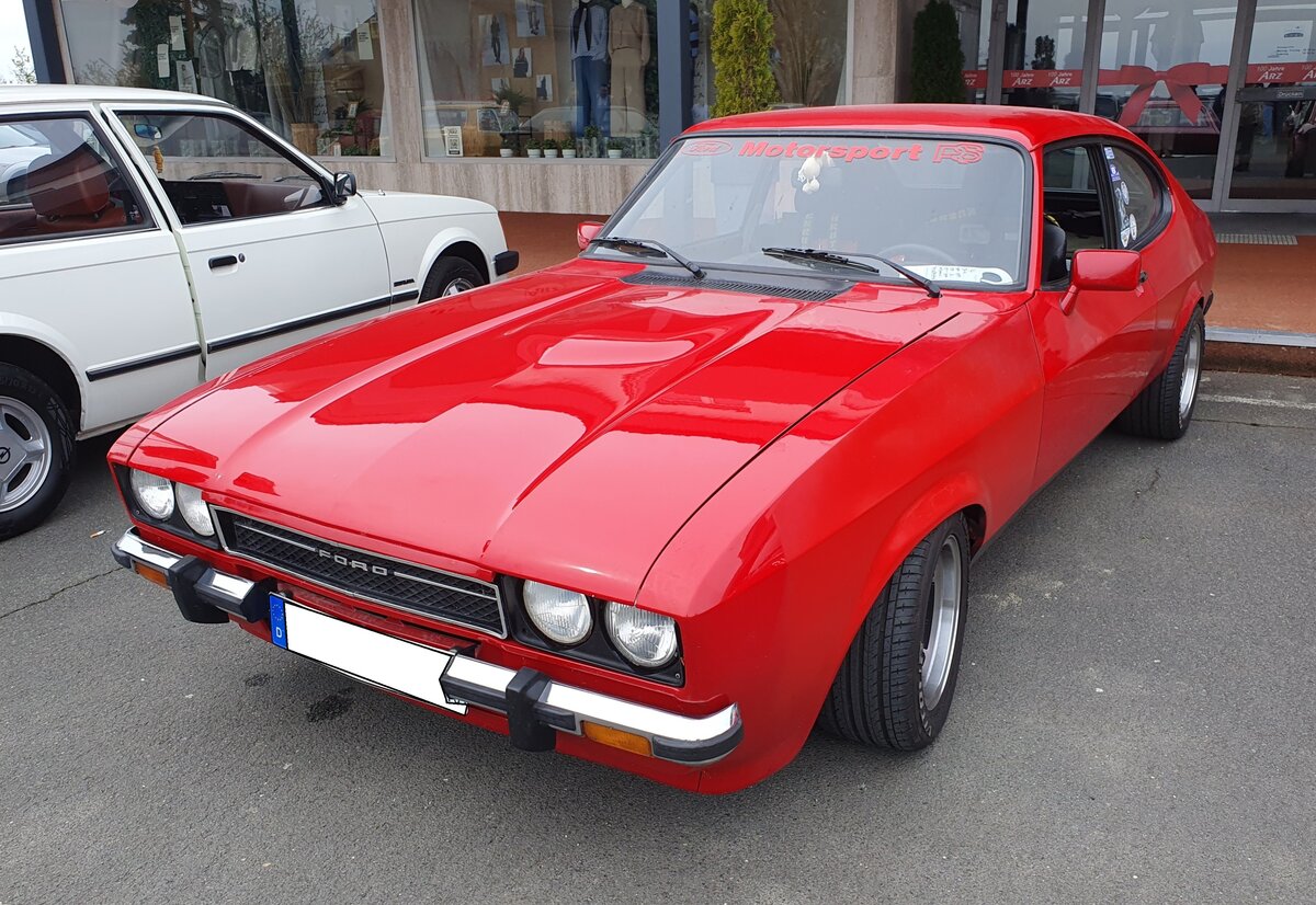 Ford Capri 3 2.0 S im Farbton kardinalrot, gebaut von 1978 bis 1986. Bei der 2,0 Liter-Variante des Capri 3 muss man genau unter die Motorhaube schauen, da Ford zwei v�llig unterschiedliche Motorenkonzepte mit identischem Hubraum f�r dieses Modell anbot: Das war zum Ersten der so genannte  Pinto-Motor , ein Vierzylinderreihenmotor mit einem Hubraum von 1993 cm� und einer Leistung von 101 PS und zweitens der so genannte  K�ln V6  mit einem Hubraum von 1999 cm� und einer Leistung von 90 PS. 66 kW / 90 PS. Dieser hatte zwar weniger Leistung, �berzeugte aber durch den typisch kernigen Sechszylinder-Klang und hohe Laufruhe und war daher bei den meisten Kunden erste Wahl. Oldtimertreffen Lorch-Ransel am 12.04.2026.