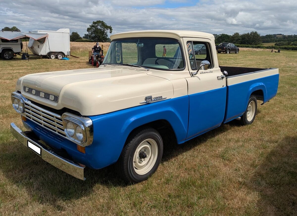 Ford F100 Custom Cab aus dem Jahr 1959 in der Farbkombination academy blue/colonial white. Der 1959`er F100 geh�rt zur dritten Generation der legend�ren F100 Serie. Ab diesem Zeitpunkt �nderte Ford das Design der Pickup-Trucks von reinen Nutzfahrzeugen, hin zu stilpr�genden Karosserien. Erstmalig konnte das Modell nun auch mit werksseitigem Allradantrieb bestellt werden. Die gehobene Version hie�  Custom Cab  (Foto) und bot mehr Komfort, Chrom-Zierelemente und eine Zweifarbenlackierung. Insgesamt setzte Ford 1959 331.348 Pickup´s zu einem Preis ab US$ 1932,00 ab. Es standen drei verschiedene Motoren zur Auswahl, wobei die V8-Aggregate besonders beliebt waren: Ein Sechszylinderreihenmotor mit einem Hubraum von 223 cui (3654 cm�) mit 145 PS, sowie zwei V8-Motoren mit 272 cui (4457 cm�) mit 181 PS und 292 cui (4785 cm�) mit 186 PS. Classic car meeting in Pontypool/South Wales am 17.05.2025.