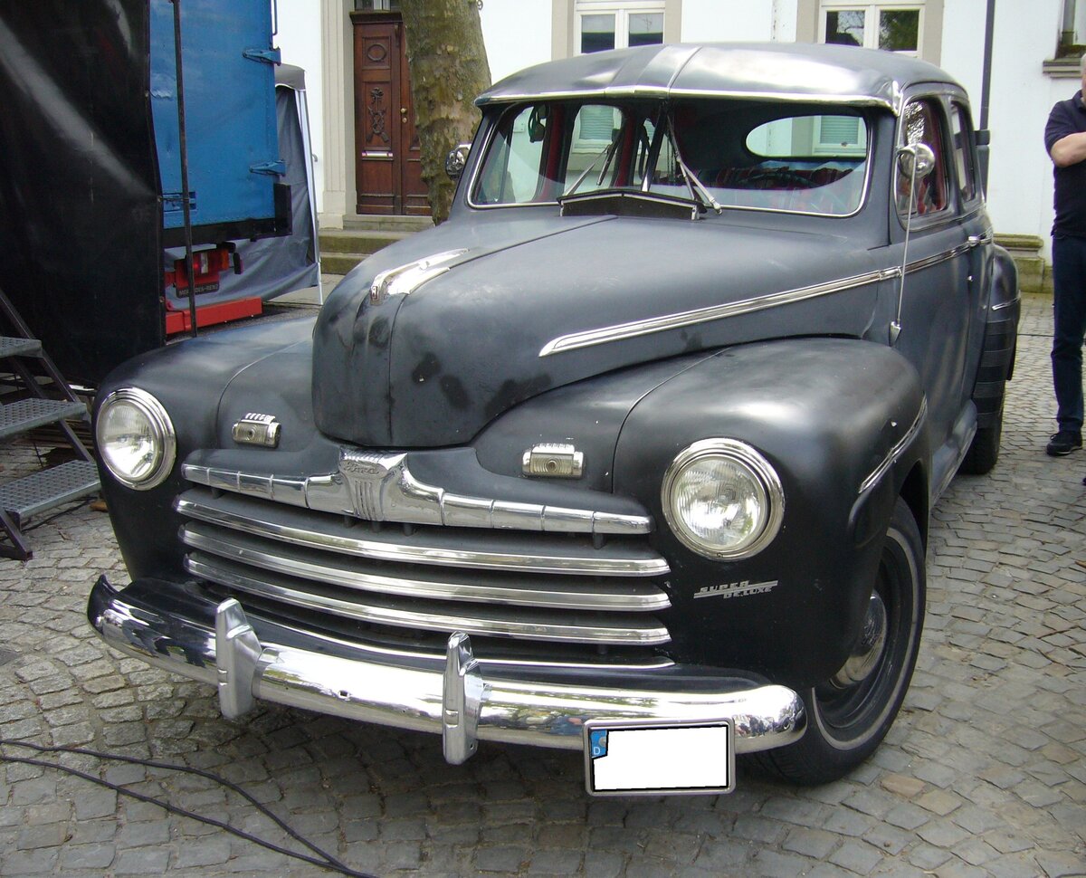Ford Fordor Super DeLuxe der Modelljahre 1946 und 1947. Zwei Monate vor der Kapitulation Japans im WW2 lief bei Ford schon wieder die PKW-Produktion an. Es wurden die optisch leicht modifizierten Vorkriegsmodelle produziert. Es gab die Baureihen DeLuxe und Super DeLuxe. Der Super DeLuxe ist zusätzlich mit einem Lenkrad mit Hupenknopf, zwei Sonnenblenden, Armstützen an allen Türen, Halteschlaufen an der B-Säule, Kissen auf der hinteren Sitzbank und einer verchromten, seitlichen, Zierleiste ausgestattet. Der Kunde konnte zwischen einem Sechszylinderreihenmotor mit einem Hubraum von 3700 cm³ und 90 PS oder einem V8-Motor mit einem Hubraum von 3910 cm³ und einer Leistung von 100 PS. Allein von der viertürigen Fordor-Variante verkaufte Ford im Jahr 1946 101.302 Fahrzeuge zu einem Preis ab US$ 1003,00. 15. Oldtimertreffen des AMC Essen-Kettwig am 01.05.2023.