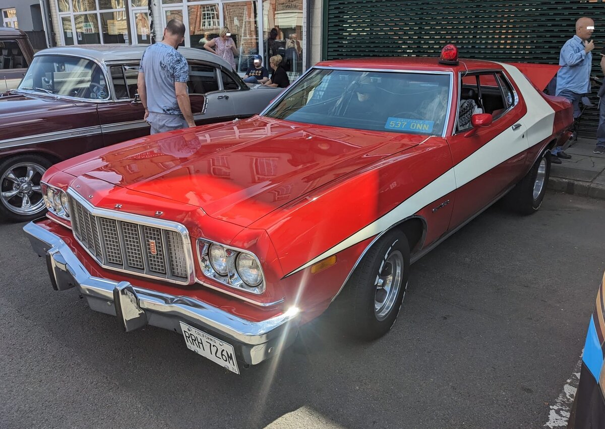 Ford Gran Torino Fastback aus den Modelljahren 1974 bis 1976. Bekannt geworden ist dieses Modell durch die US-Amerikanische Fernsehserie  Starsky & Hutch . Die Lackierung, die dem Wagen Spitznamen  Striped Tomatoe  einbrachte, war zunächst ausschließlich für die Filmproduktion entwickelt worden. Aufgrund der großen Kundennachfrage legte Ford/USA im Jahr 1976 eine limitiertes Sondermodell auf, das entsprechend dem Vorbild aus der Fernsehserie lackiert war. Das Sondermodell wurde auf der Chicago Auto Show im Februar 1976 vorgestellt. Ab März 1976 wurden genau 1.000 Stück dieses Sondermodelles gebaut und an den Mann/Frau gebracht. Der V8-Motor des Sondermodells hat einen Hubraum von 5751 cm³ und leistet, je nach Bundesstaat, 152 PS oder 154 PS. Classic car meeting in Brynmawr/South Wales am 28.07.2024.