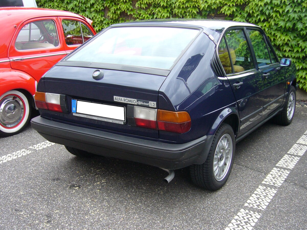 Heckansicht eines Alfa Romeo Alfasud der letzten Serie, wie er von 1980 bis 1983 produziert wurde. Bereits 1972 wurde der kompakte Alfasud vorgestellt. Der Wagen sollte die Alfa Romeo Produktpalette nach unten abrunden. Er wurde im Werk Pomigliano bei Neapel produziert. Dieses Werk wurde für die Produktion des Modells extrem erweitert um im strukturschwachen Süditalien Arbeitsplätze zu schaffen. Allerdings wurde dieses Werk häufig bestreikt und anderweitigen Arbeitsniederlegungen  lahm gelegt . Der abgelichtete Alfasud ist ein seltenes dreitüriges Modell und ist im Farbton blu procida lackiert. Der Vierzylinderboxermotor hat einen Hubraum von 1186 cm³ und leistet 68 PS. Besucherparkplatz der Düsseldorfer Classic Remise am 07.06.2021.