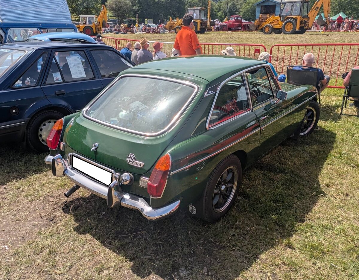 Heckansicht eines MG B GT 1800. Der MG B Roadster wurde bereits 1962 eingef�hrt. Im Oktober 1965 kam der als 2+2 Sitzer ausgelegte MG B GT zus�tzlich auf den Markt. Er war, genau wie der Roadster, bis 1980 im Verkaufsprogramm der Marke aus Coventry. W�hrend sich das Roadster Modell w�hrend der gesamten Produktionszeit fast 400.000 mal verkaufte, wurde vom GT Modell genau 125.282 Einheiten abgesetzt. Der Vierzylinderreihenmotor hat einen Hubraum von 1798 und leistet 92 PS. Die H�chstgeschwindigkeit lag bei 168 km/h. Der gezeigte Wagen wurde im Jahr 1970 produziert und d�rfte im Farbton brookland green lackiert sein. Abergavenny Steam and Vintage Show am 27.05.2023.