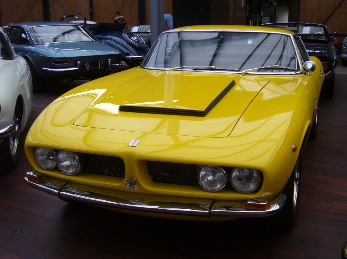 Iso Grifo GL 7.0 Litri. Das Sport-Coupe Iso Grifo kam bereits im Jahr 1964 auf den Markt und wurde optisch fast unverändert bis ins Jahr 1974 produziert. Von 1968 bis 1970 stand auch der gezeigte 7.0 Litri im Verkaufsprospekt der Marke aus Bresso bei Mailand. Optisch sind diese Fahrzeuge an der Hutze auf der Motorhaube, dem so genannten  Penthouse , erkennbar. Der aus dem Regal von GM (Chevrolet) stammende V8-Motor des 7.0 Litri hat einen Hubraum von 6998 cm³ und leistet genau 400 PS. Die Höchstgeschwindigkeit lag bei ca. 275 km/h. Classic Remise Düsseldorf am 30.10.2023.