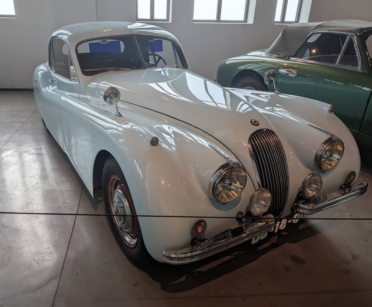 Jaguar XK 120 FHC, wie er von 1951 bis 1954 im Stammwerk Coventry vom Band lief. Der abgelichtete XK120 FHC (F ixed H ead C oupe) ist im Farbton old english white lackiert. Das 2.678 mal produzierte Coupe ist mit einem Sechszylinderreihenmotor ausgerüstet, der aus einem Hubraum von 3.442 cm³ ca. 160 PS leistet. Die Höchstgeschwindigkeit wurde damals vom Werk mit 195 km/h angegeben. Museo Automovilistico de Malaga/Spanien am 22.03.2026.