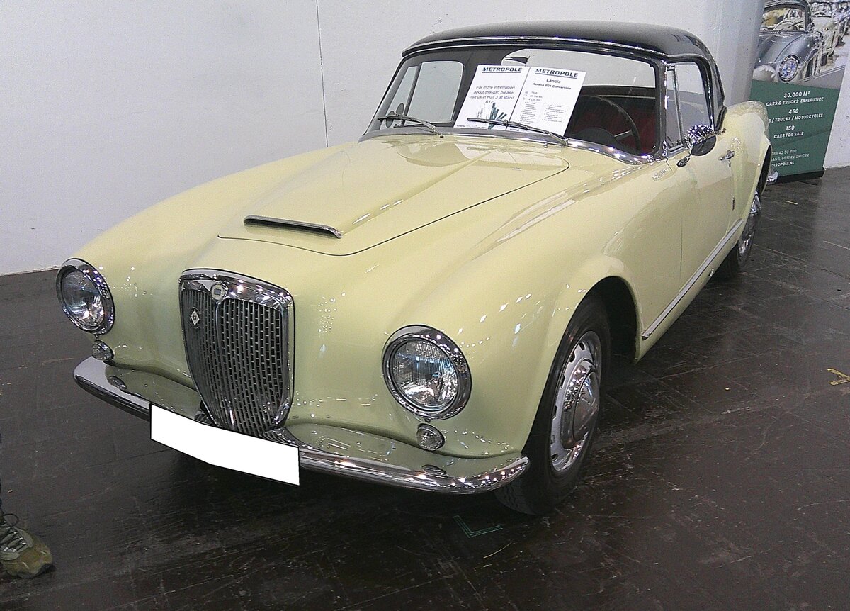 Lancia Aurelia B24 Convertibile aus dem Jahr 1956. Auf der Basis des Aurelia B24 Spider mit seiner spartanischen, aber sportlich ausgelegten, Ausstattung kam 1956 der  zivilere  Aurelia B24 Convertibile auf den Markt. Im Gegensatz zum Spider mit seiner tief ausgeschnittenen Panoramascheibe und Steckscheiben besitzt dieses Modell eine konventionelle Windschutzscheibe, Kurbelfenster und ein verbessertes, weil wetterfestes Verdeck. Von 1956 bis 1958 wurden lediglich 521 Exemplare produziert. Das Auto war ausschließlich als Linkslenker lieferbar. Der V6-Motor hat einen Hubraum von 2451 cm³ und leistet je nach Auslieferungsland zwischen 110 PS und 118 PS. Das gezeigte Cabrio ist zusätzlich mit dem damals optional lieferbaren Hardtopdach ausgerüstet. Retro Classics in Essen am 09.04.2026.