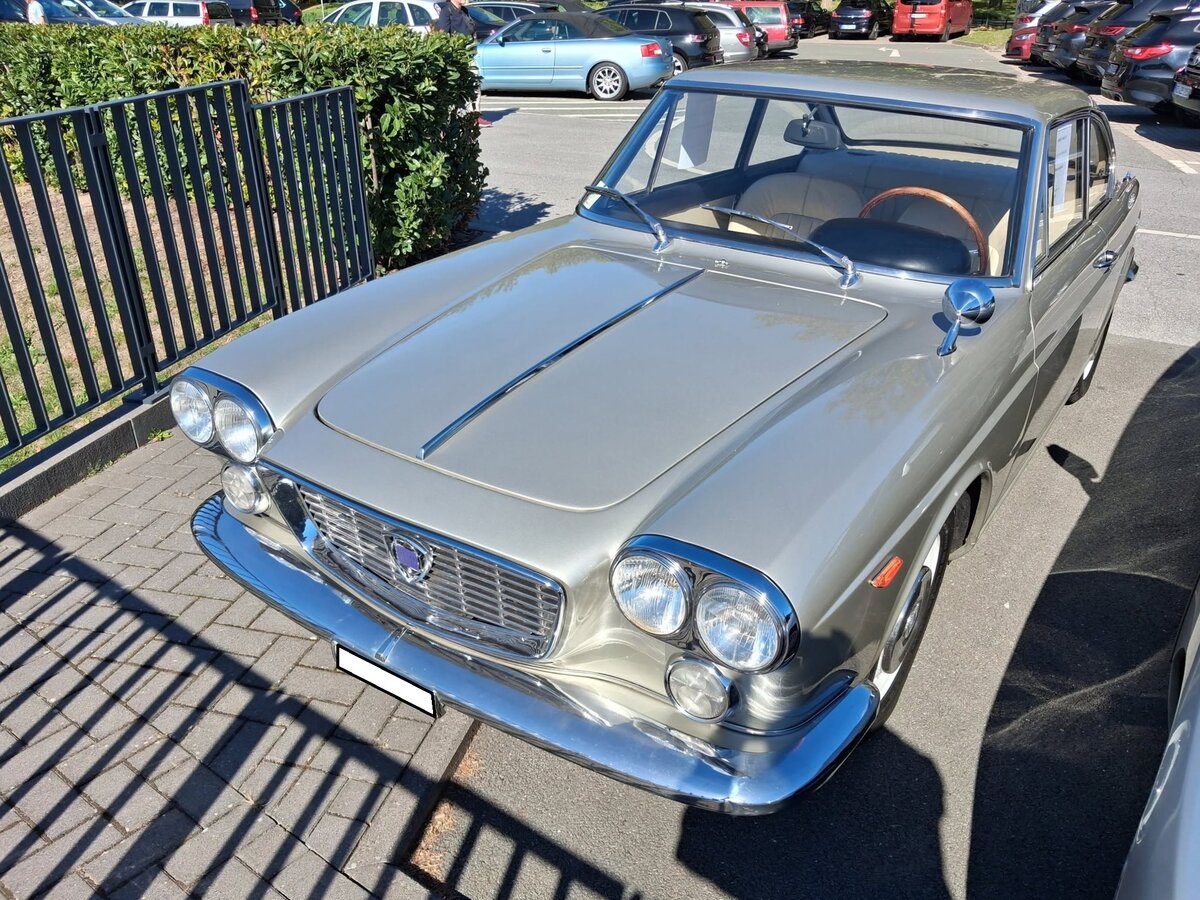 Lancia Flavia Coupe 1.8. Die Baureihe Flavia war der erste italienische Serienwagen mit Frontantrieb und serienm��igen Scheibenbremsen rundum. Produziert wurde das Modell, das als viert�rige Limousine namens Berlina, Coupe (Foto) und Cabriolet lieferbar war, von 1962 bis 1970. Herzst�ck des Coupes ist ein komplett aus Aluminium gefertigter Vierzylinder-Boxermotor. Im Laufe der Bauzeit gab es zwei technische Ausf�hrungen des Motors: Einen Vierzylinderboxermotor mit einem Hubraum von genau 1800 cm� mit 92 PS. Ab dem Modelljahr 1965 kam noch eine Variante mit einer mechanischen Kugelfischer-Einspritzung in den Verkaufsprospekt . Sie bringt eine Leistungssteigerung um 10 PS auf 102 PS. Die Erstbesitzerin dieses Coupes aus dem Modelljahr 1966 war eine �brigens eine gewisse Sophia Loren. Besucherparkplatz der Techno Classica Salon/Dortmund am 25.09.2026.