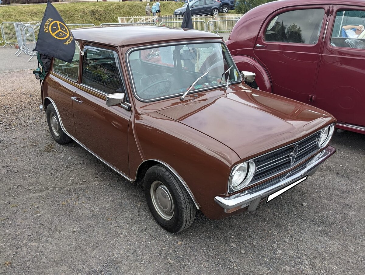Leyland Mini Clubman. Der Leyland Mini Clubman, vorgestellt im Herbst 1969 war eine optisch und technisch überarbeitete Variante des Ur-Mini. Am meisten fiel die markante, eckige, Frontpartie ins Auge. Hier konnte ich ein Modell im Farbton russet brown ablichten, wie es ab 1975 verkauft wurde. Der Vierzylinderreihenmotor hat in diesem Modell einen Hubraum von 1098 cm³ und leistet 45 PS. Classic car meeting am 13.07.2024 in Blaenavon/South-Wales. 