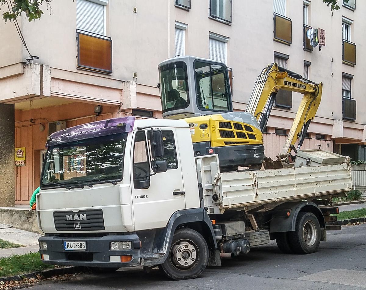 MAN LE180 trägt einen Bagger, gesehen in Pécs (HU), August 2019.