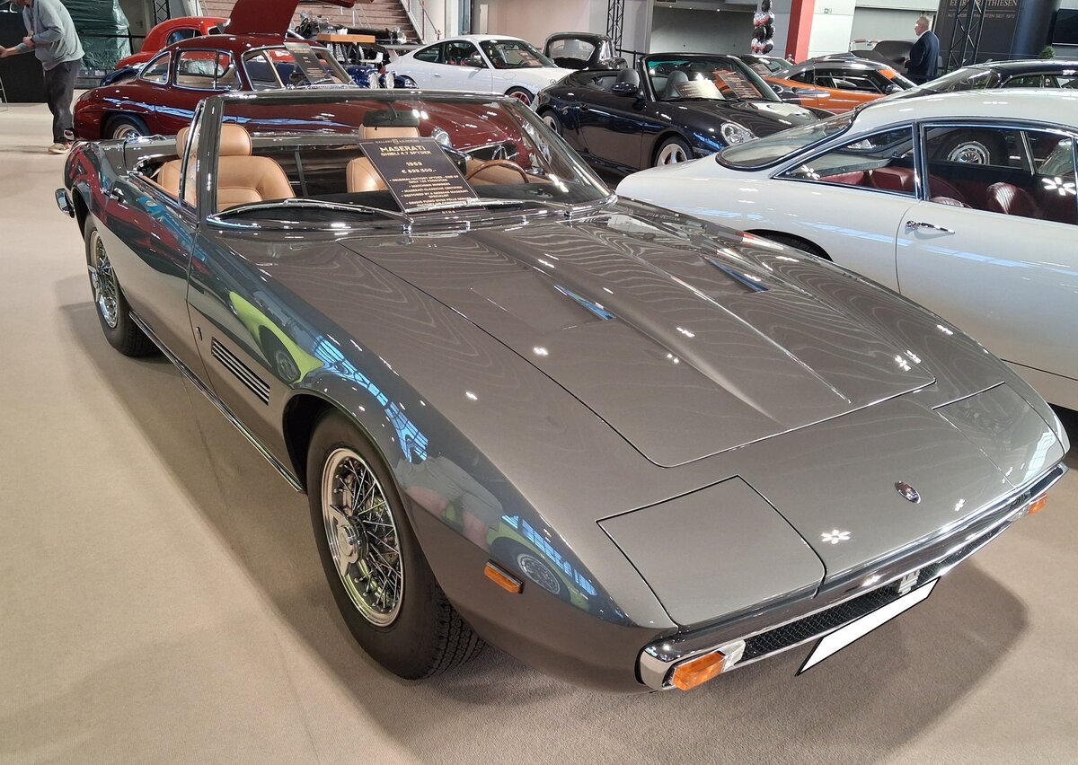 Maserati Ghibli 4.7 Spyder (Tipo AM115) aus dem Jahr 1969. Der Ghibli wurde im Herbst 1966 pr�sentiert und wurde vom jungen Giorgetto Giugiaro entworfen, der damals f�r Ghia t�tig war. Die Front ist extrem flach, die Scheinwerfer verschwinden vollst�ndig in der Karosserie und die Seitenlinie zieht sich nahezu ohne Unterbrechung bis nach hinten. W�hrend viele italienische Sportwagen jener Zeit noch relativ rund und elegant gezeichnet waren, wirkte der Ghibli pl�tzlich deutlich straffer und moderner. Im Jahr 1969 erweiterte Maserati die Modellpalette um den Ghibli-Spyder. Lediglich 125 Exemplare verlie�en das Werk als  echte  Spyder. Es gibt wohl einige nachtr�glich umgebaute Fahrzeuge. F�r Vortrieb sorgt in diesem, im Farbton argento auteil lackierten Auto, ein V8-Motor mit einem Hubraum von 4709 cm� und einer Leistung von 308 PS. Die H�chstgeschwindigkeit wurde damals mit 275 km/h angegeben. Wenn man bedenkt, das dieses Auto damals rund DM 73.000,00 gekostet hat und heute f�r rund � 700.000,00 angeboten wird, war die Anschaffung damals ein gutes Investment! Techno Classica Salon/Dortmund am 25.09.2026.