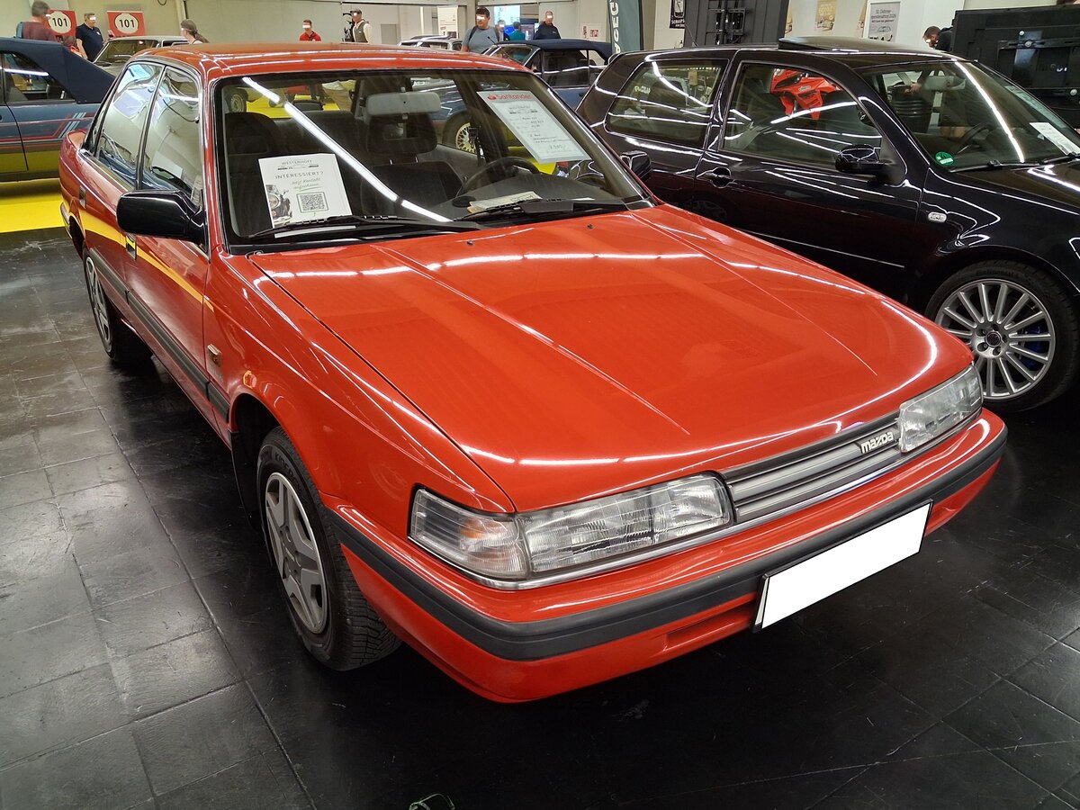 Mazda 626 Stufenhecklimousine der Baureihe GD aus dem Jahr 1988. Die Autos der 626-Baureihe GD rollten ab Oktober 1987 �ber Deutschlands Stra�en. Die Baureihe war als viert�rige Stufenheck- oder Schr�ghecklimousine, als zweit�riges Coupe und f�nft�riges Kombimodell lieferbar. Im Jahr 1988 war das Modell mit 48.911 Fahrzeugen, der meistverkaufte Importwagen in Deutschland. Basismotorisierung war ein Vierzylinderreihenmotor mit einem Hubraum von 1998 cm� und einer Leistung von 90 PS. Dieser 626´er d�rfte im damals sehr beliebten Farbton sunrise red lackiert sein. Techno Classica Salon in Dortmund am 25.09.2026.