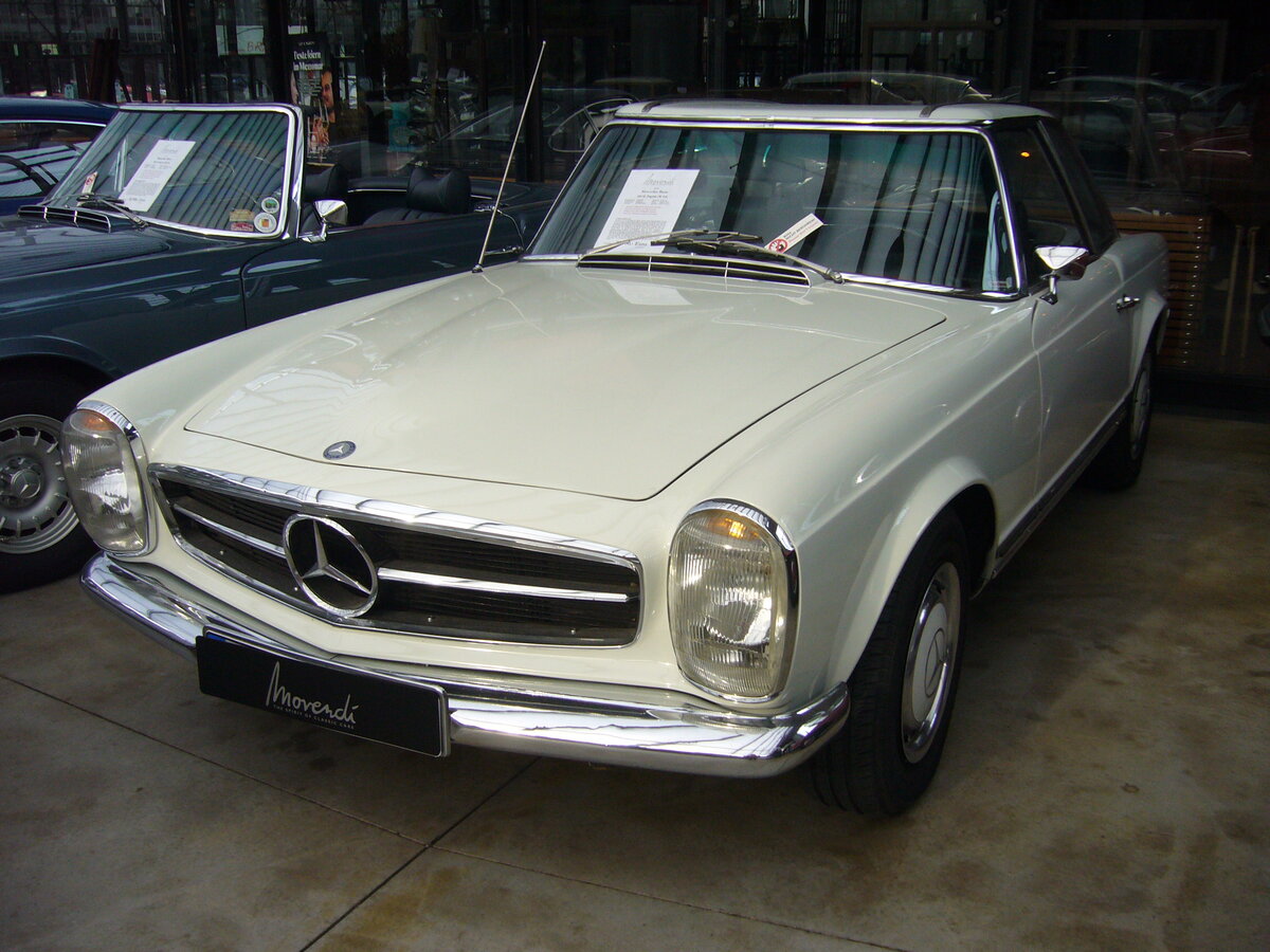 Mercedes Benz W113 280SL (E28) im Farbton papyrusweiß aus dem Jahr 1970. Mercedes Benz W113 (E28) 280SL. Produziert wurde der Sportwagen in den Jahren von 1968 bis 1971. Als Typ 230SL war der Zweisitzer bereits im Jahr 1963 erschienen. Der 280 SL war das stärkste Modell der sogenannten  Pagoden-Baureihe . In der Version 280SL verkaufte sich das Modell genau 23.885 mal. Der Sechszylinderreihenmotor leistet 170 PS aus einem Hubraum von 2778 cm³. Die Höchstgeschwindigkeit wurde damals mit 200 km/h angegeben. Classic Remise Düsseldorf am 30.10.2023.
