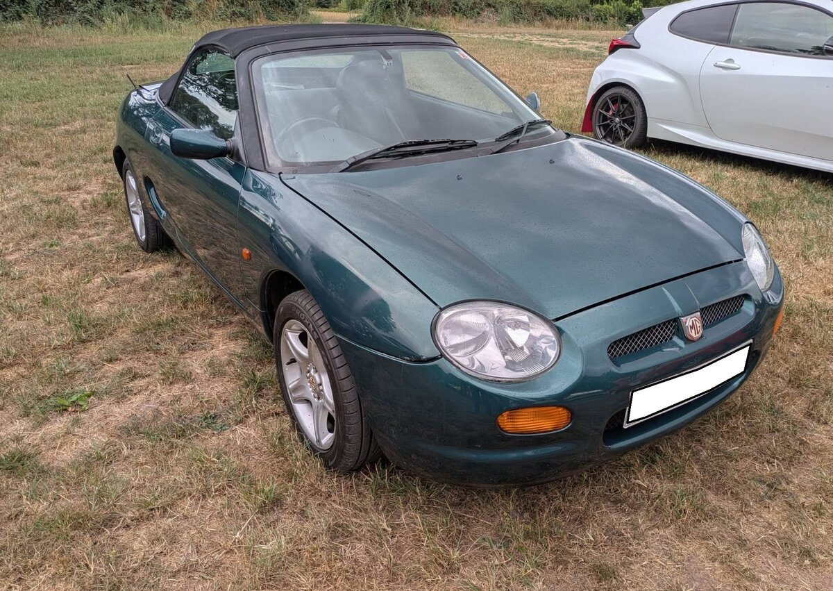 MG F MK1, also der ersten Generation, wie er von 1995 bis 1999 vom Band lief. Der hier gezeigte  F MK1  aus dem Jahr 1996 d�rfte im damaligen Farbton british racing green pearleffect lackiert sein. Da zu diesem Zeitpunkt BMW bei Rover schon das  Sagen  hatte, wurde das Modell nicht in den Hauptabsatzmarkt USA exportiert, um den Verkauf des BMW Z3 keine Konkurrenz zu machen. Der Vierzylinderreihenmotor mit einem Hubraum von 1796 cm� war mit 120 PS und 146 PS Leistung lieferbar. Treffen des Chainbridge classic car club auf der Wiese vor einem Pub in Chainbridge/Wales im Juli 2025.