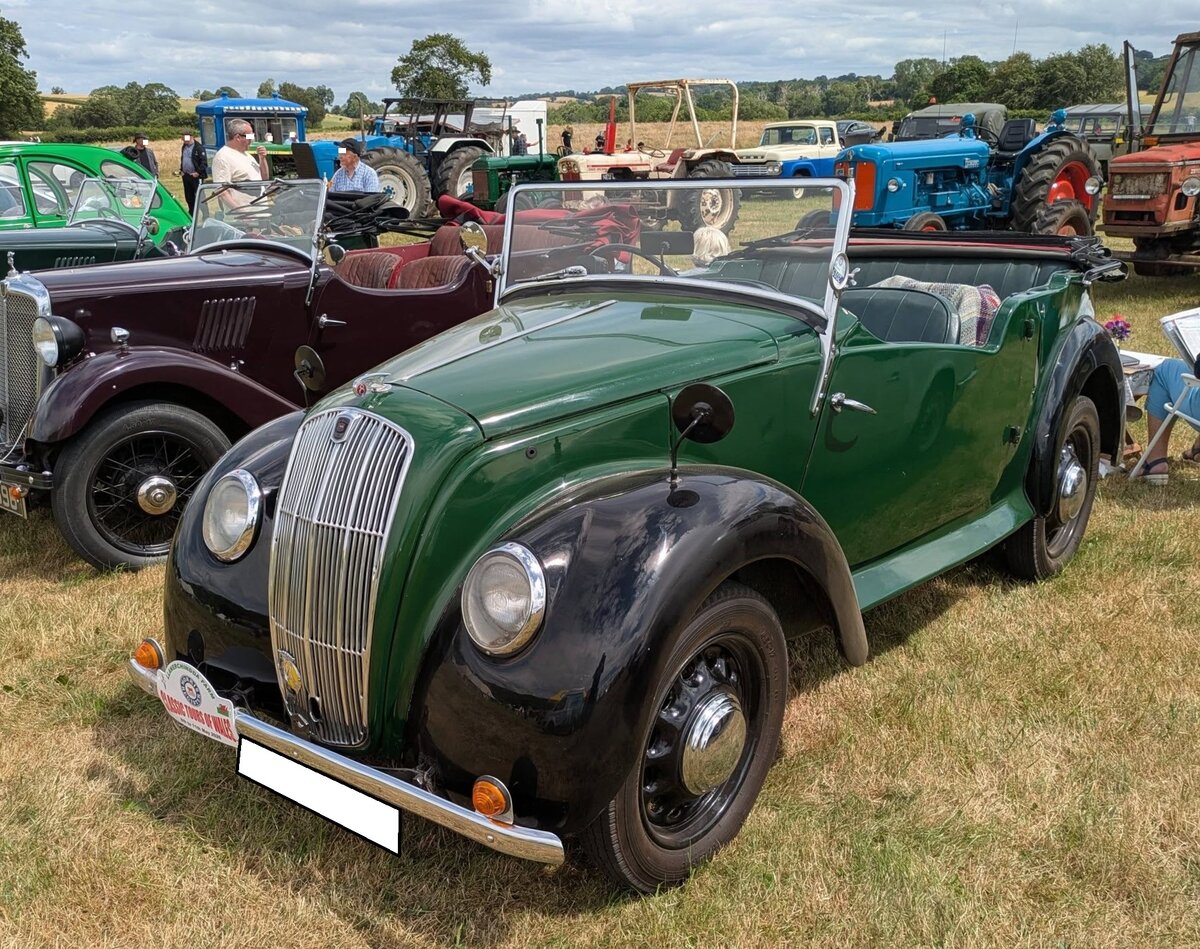 Morris Eight Series E Tourer aus dem Jahr 1939. Die Kleinwagen-Baureihe Morris Eight wurde bereits Mitte der 1930´er Jahre auf den Markt gebracht. Bereits 1937 wurde der Series 1 durch den optisch �berarbeiteten, aber technisch fast identischen Morris Eight Series II abgel�st. Das letzte Modell der Baureihe  Eight  war der gezeigte Series E, der kurz vor Beginn von WW2 auf den Markt kam. Das Modell war als Open Tourer (Foto) oder viert�rige Limousine namens Saloon zu bekommen. Das markanteste Merkmal dieses Modelles ist der damals sehr modern gewesene K�hlergrill im sogenannten  Wasserfall-Design . W�hrend des Krieges wurde das Modell f�r das Milit�r, auch als geschlossener Kastenlieferwagen, weiter gebaut. Nach WW2 wurde bis ins Jahr 1948 nur noch die Limousine produziert. Der Vierzylinderreihenmotor hat einen Hubraum von 918 cm� und leistet genau 30 PS. Der  Eight Tourer  d�rfte im Farbton sage green lackiert sein. Classic car meeting in Pontypool/South Wales am 17.05.2025.