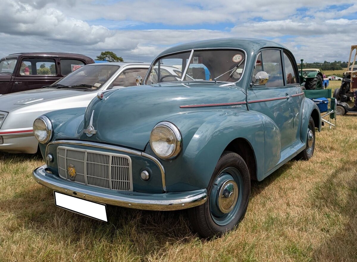 Morris Minor Series 2 zweit�rige Limousine im Farbton birch grey aus dem Jahr 1954. Als Morris Minor MM kam dieses Modell 1948 auf den Markt. Im Jahr 1952 fusionierten die Marken Austin und Morris zur BMC (B ritish M otor C orporation). Zeitgleich wurde der optisch und technisch modifizierte Morris Minor vorgestellt. Das Modell war als zwei- und viert�rige Limousine und als viert�rige Cabrio-Limousine lieferbar. 1953 kam noch das dreit�rige Modell  Traveller  hinzu. Es war ein Kombimodell mit hinterem Holzaufbau. Schnell avancierte der Minor zum britischen  Volkswagen . Der Vierzylinderreihenmotor des Minor Series 2 hat einen Hubraum von 803 cm� und leistet 30 PS. 1956 folgte dann der Minor 1000, der noch sage und schreibe 16 Jahre gebaut wurde. Optisch kann man den Series 2 Minor am besten vom Minor 1000 durch die geteilte Frontscheibe unterscheiden. Classic car meeting in Pontypool/South Wales am 17.05.2025.