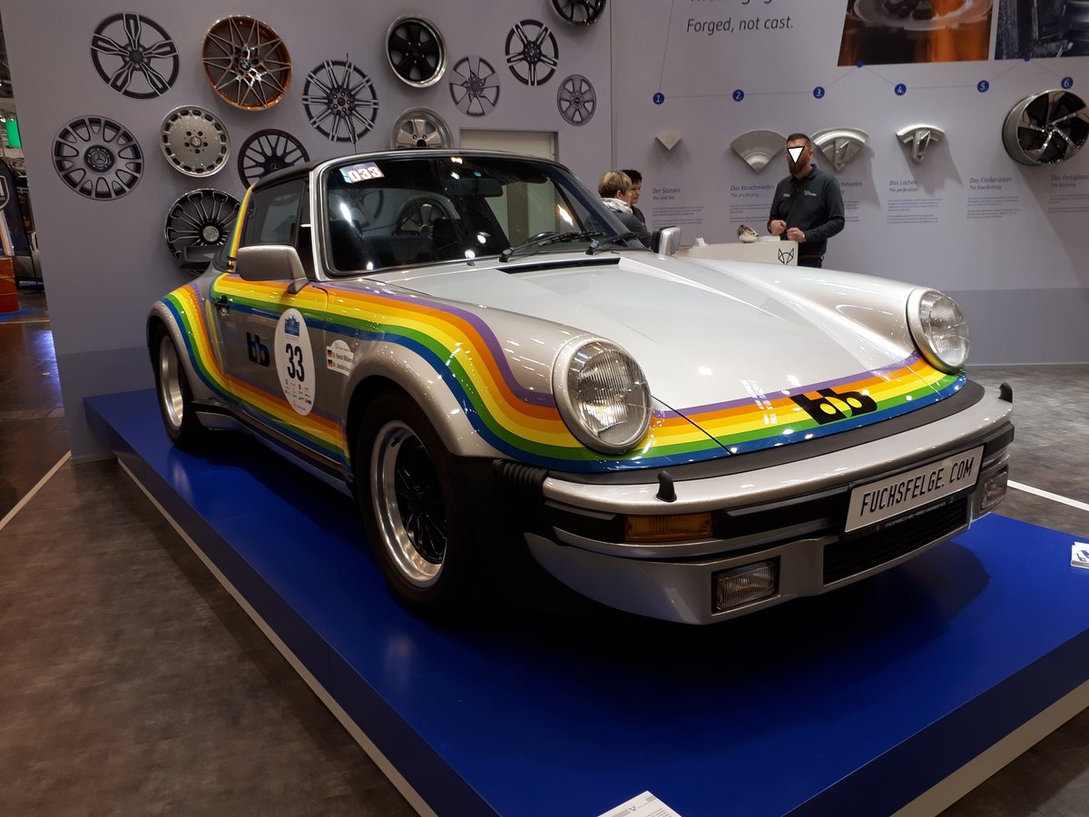 Nachbau des legendären  Regenbogen-Porsche . Im Jahr 1976 gab es den Porsche 911 Targa und den Porsche 911 Turbo. Rainer Buchmann mit seiner Firma bb blieb es vorbehalten, den ersten Porsche 911 Turbo-Targa zu kreieren. Ursprünglich wurde der schillernde bb Porsche für den Messeauftritt des Kameraherstellers Polaroid zur Photokina des Jahres 1976 gebaut. Daher resultiert auch sein unverwechselbares Design, die ringsum laufenden Streifen in den sechs Regenbogenfarben. Außerdem wurde der Wagen mit handgeschmiedeten Fuchs-Felgen versehen. In dem Kinofilm  Car-Napping  spielte der  Regenbogen-Porsche  die Hauptrolle. Techno Classica Essen am 24.03.2018.