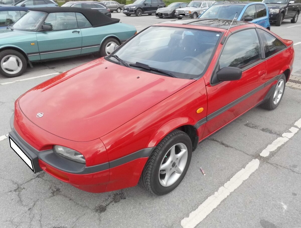 Nissan 100NX der Serie B13. Der NX100 basierte auf dem Nissan  Sunny  der Baureihe N14 und wurde von 1990 bis 1995 produziert. In Deutschland wurde das Modell ab dem Fr�hjahr 1991 verkauft. Eine Besonderheit des 100NX war das abnehmbare Targadach. Das Modell war mit etlichen Vierzylinderbenzinmotoren in der Bandbreite von 1.5 Litern Hubraum bis 2.0 Litern Hubraum lieferbar. Das Leistungsspektrum reichte dabei von 90 PS bis 143 PS.  Besucherparkplatz der Retro Classics Essen im April 2026.