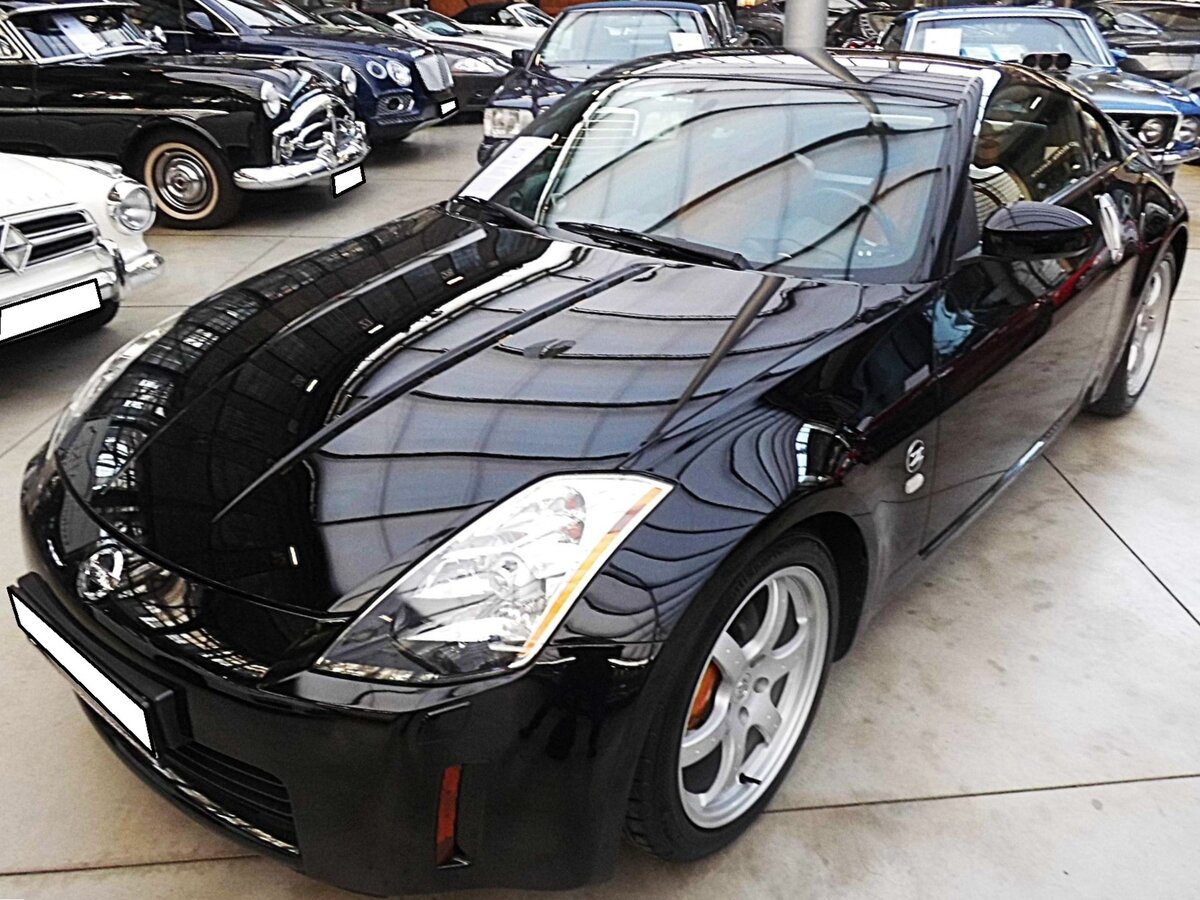 Nissan 350Z Coupe. Der 350Z wurde im Jahr 2002 vorgestellt und stand ein Jahr später auch bei den deutschen Nissan-Händlern. Somit hatte Nissan, zwei Jahre nach der Einstellung des recht erfolgreichen Modells 300ZX, wieder einen Sportwagen im Programm, den es ab März 2005 in Deutschland auch offenen Roadster zu kaufen gab. Der V6-Motor hat einen Hubraum von 3498 cm³ und leistet, je nach Baujahr, zwischen 280 PS und 313 PS. Classic Remise Düsseldorf am 15.01.2026.
