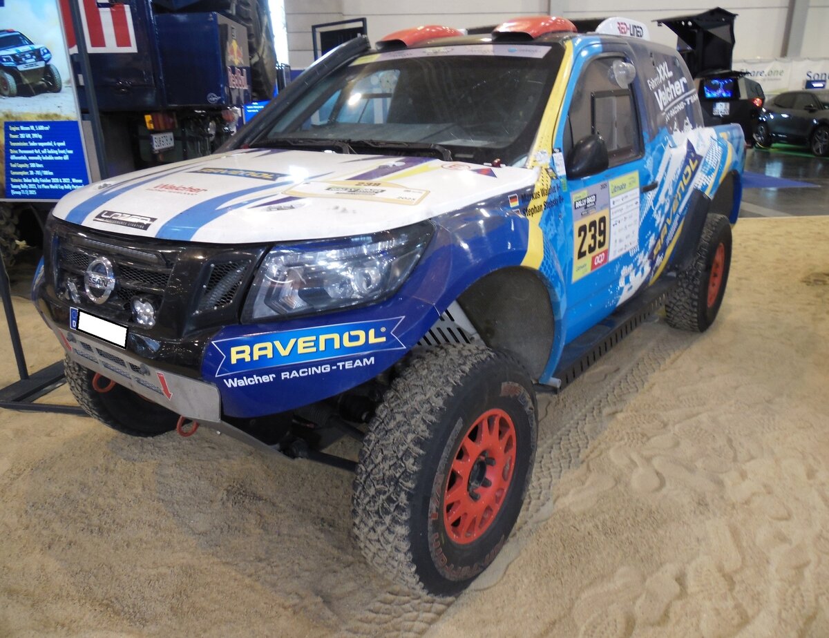 Nissan Navara T1 V8. Teilnehmerfahrzeug der Rallye Dakar vom 02.01.2022 bis zum 14.01.2022. In diesem Auto stecken viele Jahre Entwicklungsarbeit. So wie der Navara da steht, eignet er sich für die härtesten Cross-Country-Rennen und Rallyes. Die Basis bildet ein speziell für die harten Bedingungen von Rallyes gefertigter Rohrrahmen, gepaart mit Komponenten höchster Qualität, wie dem 5,6-Liter-V8-Motor aus der hauseigenen Motorsportabteilung von Nissan, dem sequenziellen 6-Gang-Getriebe der Marke Sadev, sowie der speziellen Doppelstoßdämpfer des Herstellers Reiger. Aufgebaut wurde das Fahrzeug vom südafrikanischen Rallye-Experten  Red-Lined“ aus Kyalami bei Johannesburg. Essen Motor Show am 28.11.2025.