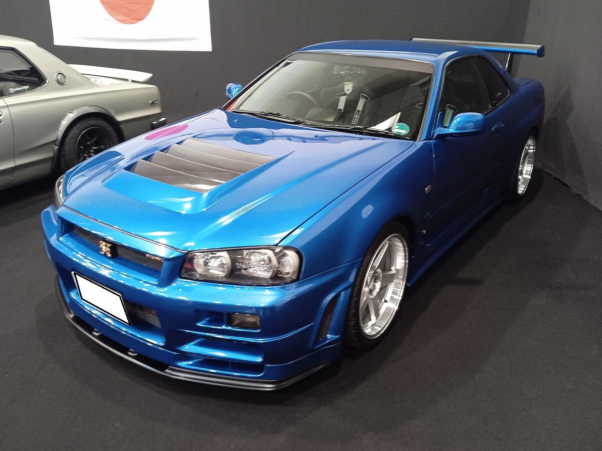 Nissan Skyline R34GTR, wie er von 1999 bis 2002 produziert wurde. Er war die sportliche Coupe-Version, der ein Jahr vorher präsentierten Limousine R34. Das Modell war in etlichen Ausstattungs- und Motorisierungsversionen für ambitionierte Sportfahrer lieferbar.  Basismotorisierung  war ein Sechszylinderreihenmotor mit einem Hubraum von 2568 cm³ und einer Leistung zwischen 280 PS und 299 PS. Der mittels Allrad angetriebene R34GTR erreicht eine Höchstgeschwindigkeit von rund 250 km/h. Essen Motor Show am 28.11.2025.