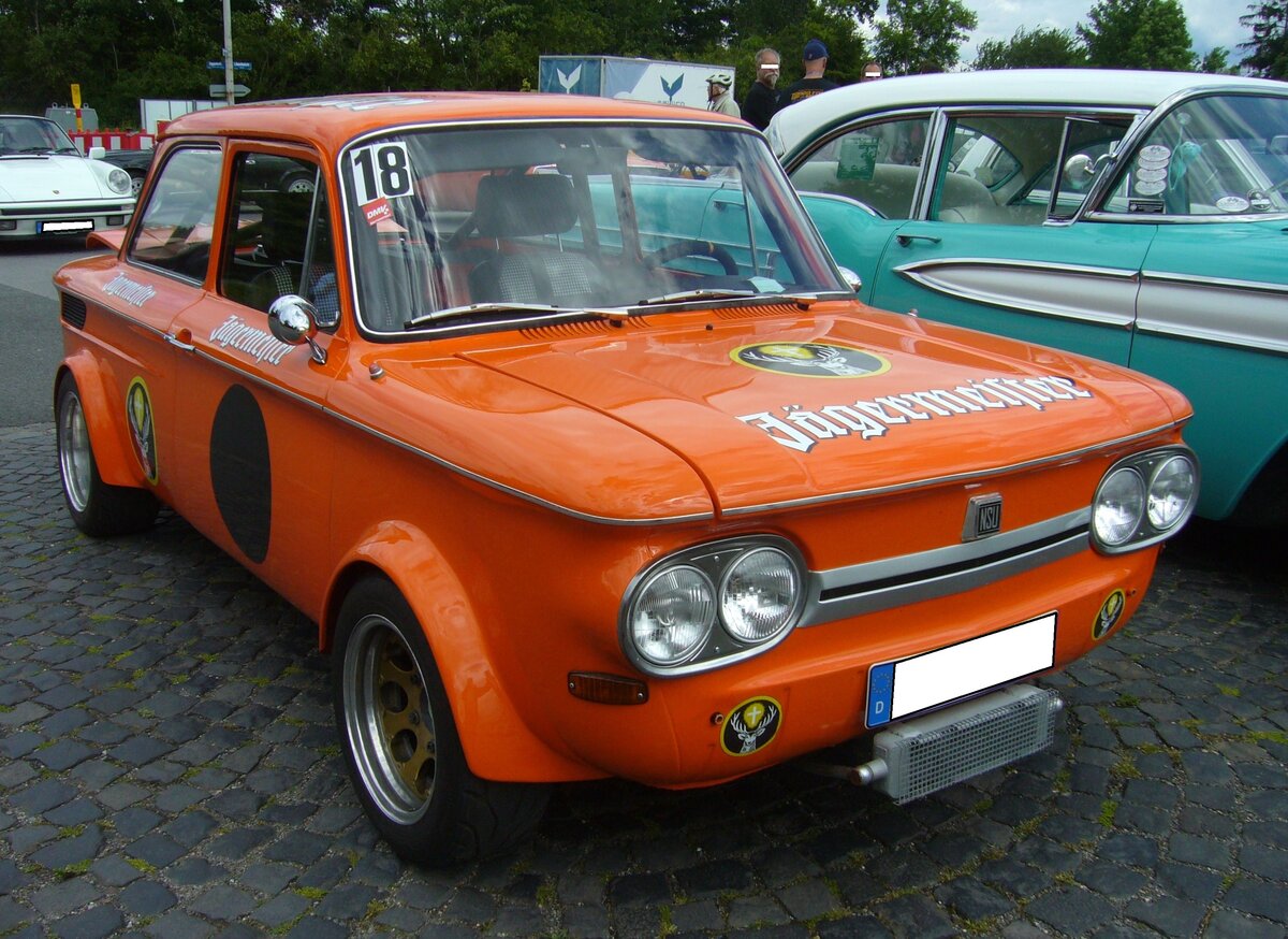 NSU TT, gebaut in Neckarsulm in den Jahren von 1968 bis 1972. Von diesem sportlichen Gebrauchswagen wurden insgesamt 64.269 Einheiten produziert. Davon 14.942 Autos mit dem 1.0l Motor und 49.327 Fahrzeuge mit dem 1.2l Motor. Der abgelichtete,  aufgebrezelte  TT, ist im zeitgemässen  Jägermeister-Orange  lackiert. Serienmäßig hat der Wagen einen, im Heck verbauten, Vierzylinderreihenmotor mit einem Hubraum von 1177 cm³. Der 65 PS starke Motor verhilft dem Wagen damit zu einer Höchstgeschwindigkeit von 153 km/h. Oldtimertreffen Flughafen Essen/Mülheim am 06.06.2022.