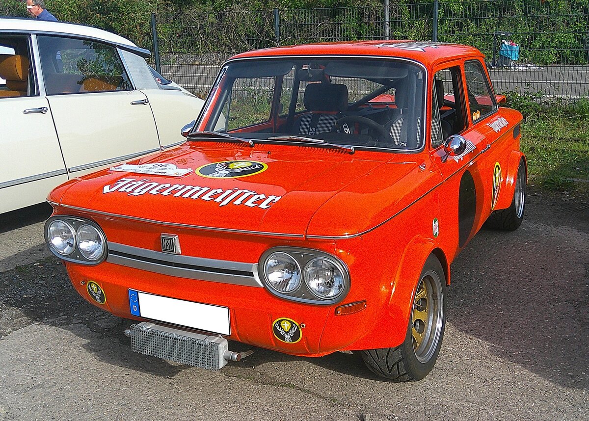 NSU TT, gebaut in Neckarsulm in den Jahren von 1968 bis 1972. Von diesem sportlichen Gebrauchswagen wurden insgesamt 64.269 Einheiten produziert. Davon 14.942 Autos mit dem 1.0l Motor und 49.327 Fahrzeuge mit dem 1.2l Motor. Der abgelichtete,  aufgebrezelte  TT, ist im zeitgem��en  J�germeister-Orange  lackiert. Serienm��ig hat der Wagen einen, im Heck verbauten, Vierzylinderreihenmotor mit einem Hubraum von 1177 cm�. Der 65 PS starke Motor verhilft dem Wagen damit zu einer H�chstgeschwindigkeit von 153 km/h. Der gezeigte TT aus dem Jahr 1968 kann allerdings mit einer PS Leistung von 110 PS aufwarten. Sammelplatz zur Landpartie des AMC M�lheim/Ruhr am 03.05.2026.