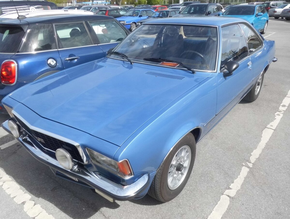 Opel Commodore B Coupe GS/E im Farbton arktisweiß. Zeitgleich mit dem Opel Rekord D wurde auch der große Bruder  Commodore B  im März 1972 auf dem Genfer Salon vorgestellt. Anfänglich konnte der Kunde zwischen zwei Sechszylinderreihenmotoren mit  Vergasern wählen. Ab September 1972 wurde die Modellpalette um das Modell GS/E erweitert. Der GS/E hat einen Hubraum von 2784 cm³ und leistet mittels einer einer elektronischen Einspritzpumpe aus dem Hause Bosch 160 PS. Zum Modelljahr 1975 wurde die Leistung auf 155 PS reduziert. Im März 1976 stand ein solches Coupe mit einem Kaufpreis von mindestens DM 21.950,00 in den Preislisten der Adam Opel AG. Besucherparkplatz der Essener Retro Classics am 09.04.2026.