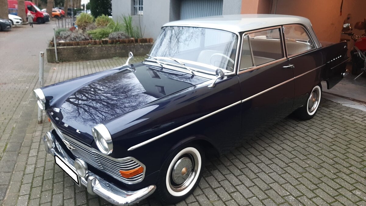 Opel Olympia Rekord P2 aus dem Jahr 1962. Opel Olympia Rekord P2, produziert von August 1960 bis Frühsommer 1963. Hier wurde eine zweitürige Limousine in der Farbkombination royalblau/alabastergrau abgelichtet. Der gezeigte Rekord ist ein 1700`er. Der stärkere 1.7l Motor mit 55 PS, kostete im Gegensatz zur Standardmotorisierung mit 1.5l und 50 PS einen Aufpreis von DM 75,00. Bis zur Produktionseinstellung im Spätsommer 1963 verließen ca. 550.000 Autos dieses Typs das Rüsselsheimer Opel-Werk. Velbert am 16.12.2023.