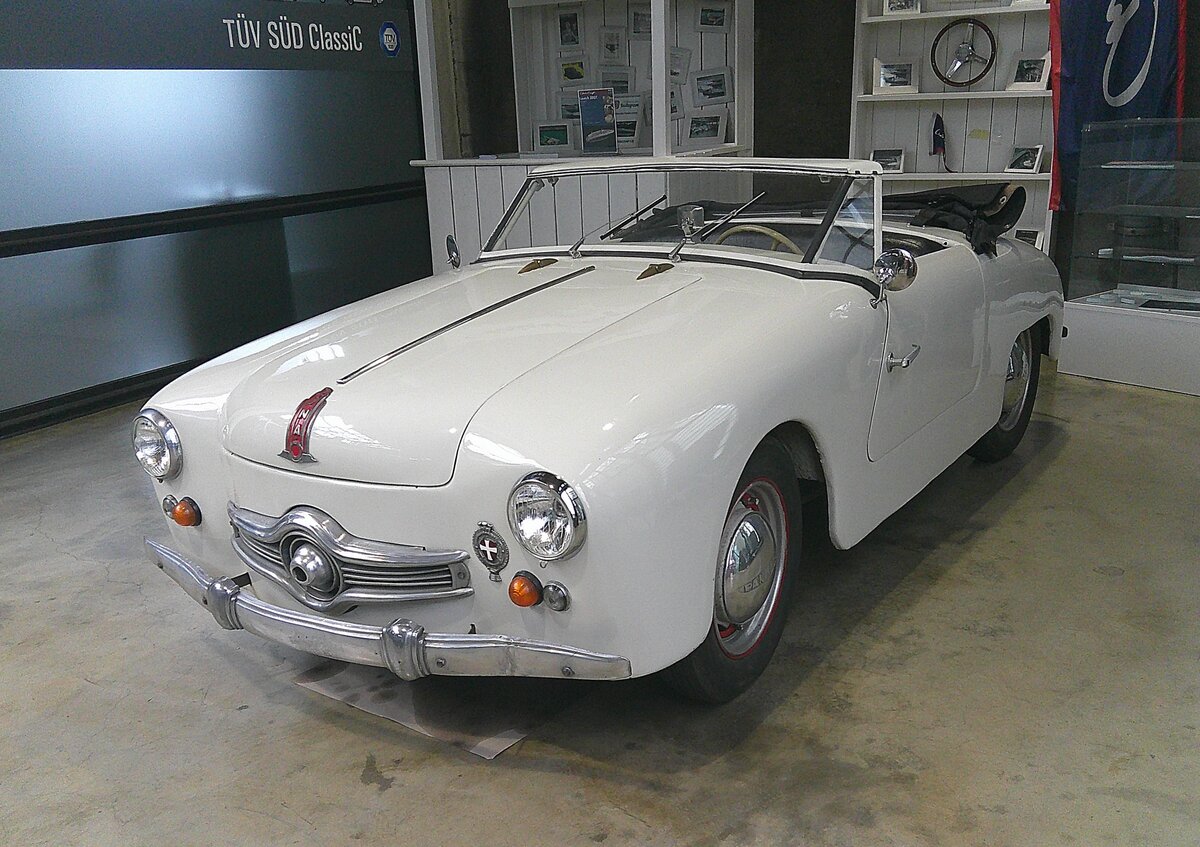 Panhard Dyna Junior X. In der unmittelbaren Nachkriegszeit gab es überall in Europa, also auch in Frankreich, Materialbeschränkungen. Dies war in allen Industriezweigen bis weit in die 1950`er Jahre spürbar. Während einige Hersteller der Automobilindustrie bei der Materialbelieferung Vorrang hatten, wie beispielsweise Renault, das mit seinem 4CV als erster Hersteller voll einsatzfähig war, mussten andere Hersteller warten und meist ihre überarbeiteten Vorkriegsfahrzeuge anbieten. In dieser tristen Automobillandschaft stach Panhard mit seinem Dyna X in seinem unverwechselbaren Stil und der Aluminiumkarosserie hervor. Von 1951 bis 1956 wurde auf dieser Basis ein hübscher, kleiner Roadster, der gezeigte Dyna Junior, gebaut. Ab 1954 wurde der vom Dyna X übernommene Kühlergrill mit der Kugel in der Mitte verbaut. In diesem Jahr wird die Version mit den vier Steuer-PS (4CV) eingestellt, so das nur noch das Cabrio im Handel bleibt. Der Zweizylinderboxermotor hat einen Hubraum von 851 cm³ und leistet 42 PS. Darüber hinaus kann das Modell mit einem MAG-Kompressor geordert werden. Mit dieser Option erhöht sich die Leistung auf 60 PS. Diese Motorleistung ist gut für eine Höchstgeschwindigkeit von rund 145 km/h. Classic Remise Düsseldorf am 15.01.2026.