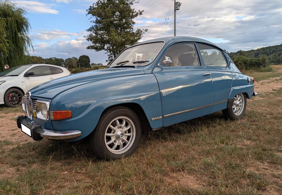 Profilansicht eines Saab 96 im Farbton carolina blue aus dem Jahr 1972. Der Saab 96 l�ste im Jahr 1960 den �hnlich gezeichneten Saab 93 ab. Ab dem Modelljahr 1966 wurden die 96´er mit dem 1.5 Liter V4-Motor aus dem Regal der K�lner Ford-Werke ausger�stet, da die vorher verbauten Dreizylinderzweitaktmotoren nicht mehr zeitgem�� waren. Dieser V4-Motor hat einen Hubraum von 1498 cm� und leistet 65 PS. Im Jahr 1978 wurde die Produktion dieses Modelles im schwedischen Stammwerk Trollh�ttan eingestellt und f�r die letzten zwei Produktionsjahre ins finnische Zweigwerk Uusikaupunki (der Ort hei�t wirklich so!) verlegt. Treffen des Chainbridge classic car club auf der Wiese vor einem Pub in Chainbridge/Wales im Juli 2025.