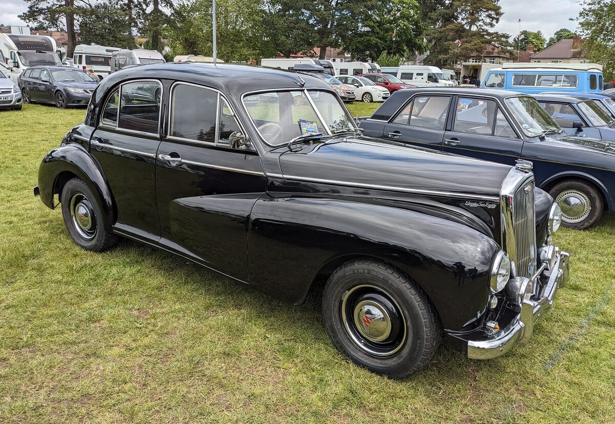 Profilansicht eines Wolseley 6/80 aus dem Jahr 1953. Der im Oktober 1948, zeitgleich mit dem Schwestermodell 4/50, eingeführte 6/80 ist vielen von uns als typischer Zivilfahrzeug von Scotland Yard in Erinnerung. Man sah ihn im deutschen Fernsehen häufig, in den damals beliebten Edgar-Wallace-Filmen, jener Zeit. Der 6/80 verkaufte sich für ein Fahrzeug dieses Marktsegments sehr gut. Nach 25.281 Fahrzeugen wurde die Produktion dieses Modelles zu Gunsten des neuen Modelles 6/90 im Herbst 1954 eingestellt. Unter der Motorhaube verrichtet ein Sechszylinderreihenmotor mit einem Hubraum von 2215 cm³ seine Arbeit. Seine Leistung von 72 PS soll das Auto auf eine Spitzengeschwindigkeit von 81 mp/h (rund 130 km/h) beschleunigt haben können. Steam and vintage show am 27.05.2024 in Abergavenny/South Wales.