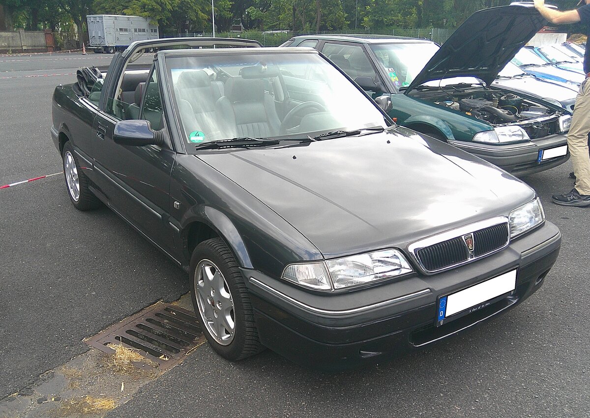 Rover 214Si Cabriolet im Farbton storm grey. Die, oft auch als  Rover 200  bezeichnete Baureihe war als Limousine, Kombilimousine, Coupe und eben als Cabriolet (Foto) lieferbar. Sie basiert auf einer Plattform, die in Zusammenarbeit mit Honda entwickelt wurde. W�hrend die Limousine schon 1989 auf den Markt kam, stand das Cabriolet erst ab 1993 bei den Vertragsh�ndlern der MG-Rover-Group. Bei uns in Deutschland sah man das Cabriolet mit den typischen �berrollb�gel im  Erdbeerk�rbchen-Look  mit Platz f�r vier Personen recht selten. F�r Vortrieb sorgt ein Vierzylinderreihenmotor mit 16V-Technik. Dieser hat einen Hubraum von 1396 cm� und leistet 103 PS. Angeblich soll eine Spitzengeschwindigkeit von 182 km/h erreicht worden sein. 10. BCMM ( B ritish C ar M otorcycle M eeting) am 19.07.2026 an Mo´s Bikertreff in Krefeld.