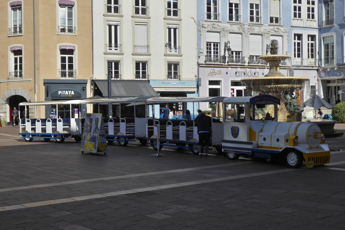 Strasseneisenbahn am Startpunkt der Rundfahrt am Brunnen „Fontaine des trois ordres“ auf dem  Place Grenette  in Grenoble. 09.2022