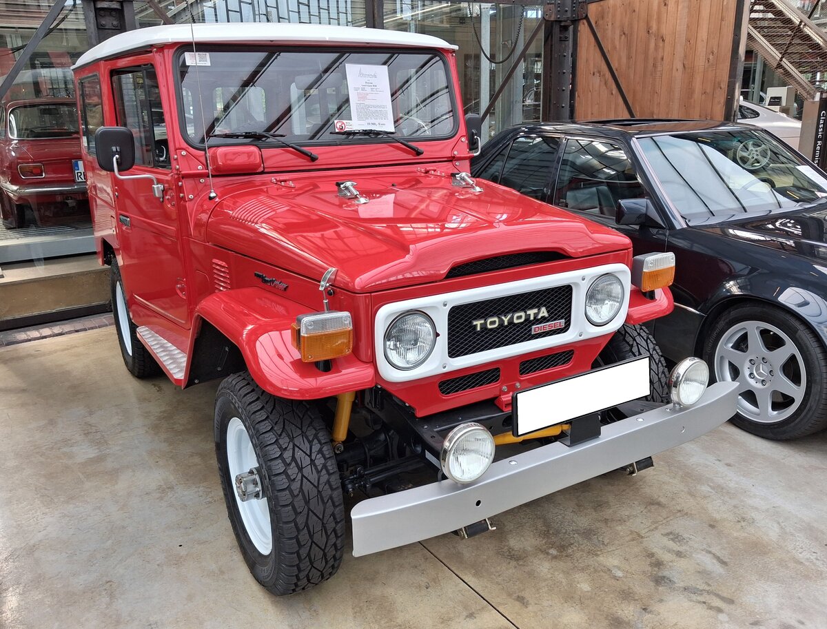 Toyota Landcruiser der Baureihe BJ40 aus dem Jahr 1980. Die Baureihe J40 kam bereits im Jahr 1960 auf den Markt, wurde permanent technisch weiter entwickelt und bis ins Jahr 1984 mit nur kleinen optischen Retuschen gebaut. Es gab die Baureihe BJ mit einem Vierzylinderreihendieselmotor und FJ mit einem Sechszylinderreihenbenzinmotor. Bei allen Fahrzeugen der J40-Baureihe konnte man das Dach und die T�ren abmontieren, um ein Cabriolet-Feeling zu genie�en. Der Dieselmotor dieses BJ40 hat einen Hubraum von 2977 cm� und leistet laut Expose 80 PS. Der gezeigte BJ40 im Farbton freeborn red wurde im M�rz 1980 erstmalig in Portugal zugelassen. Classic Remise D�sseldorf am 26.09.2026.