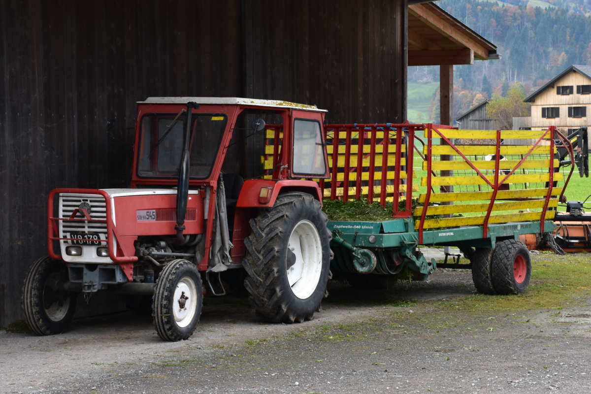 Traktor Steyr 545 mit Ladewagen Steyr Hamster Plus 17 auf einem Bauernhof in Vorarlberg (2021-10-26) [Fotostandort beim Käseverkaufsautomat].