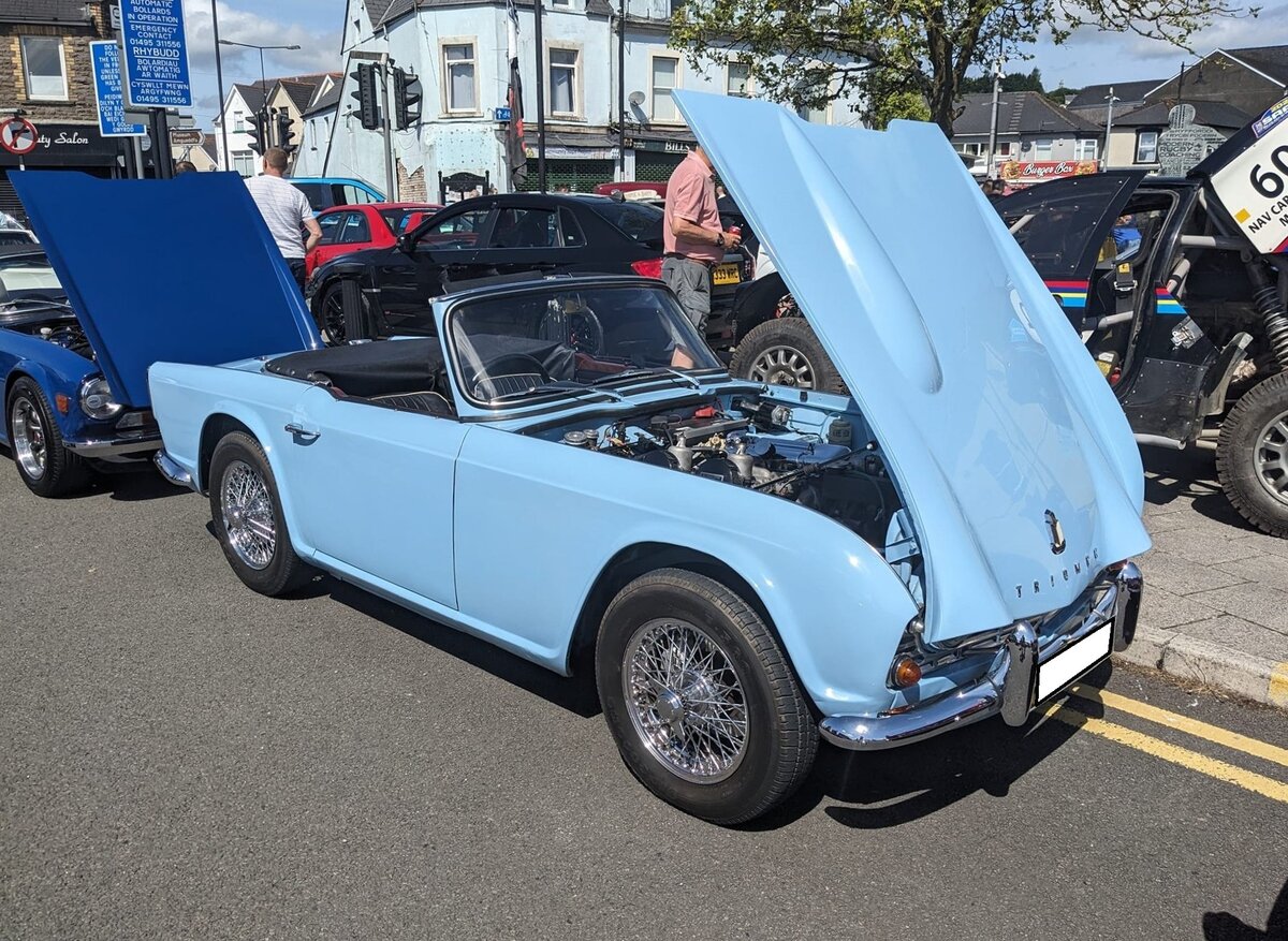 Triumph  TR4 im Farbton powder blue. Verglichen mit seinem legendären Vorgänger  TR3, bot der von Giovanni Michelotti (*1921 +1980) gezeichnete TR4, wesentlich mehr Komfort. Obwohl der TR4 über versenkbare Seitenscheiben, ein wesentlich besseres Verdeck und über einen Kofferraum verfügte, verlor er nichts von seinen sportlichen Qualitäten. Mit dem völlig neuen Vierzylinderreihenmotor mit einem Hubraum von 2138 cm³ und einer Leistung von 105 PS erreichte das Modell ein Leistungsniveau das sich ohne weiteres mit den Konkurrenten in dieser Kategorie messen konnte. Die Höchstgeschwindigkeit wurde mit 175 km/h angegeben. Der relativ günstige Preis sorgte von 1962 bis 1965 für ein Produktionsvolumen von rund 40.000 Fahrzeugen. Classic car meeting in Brynmawr/South Wales am 28.07.2024.