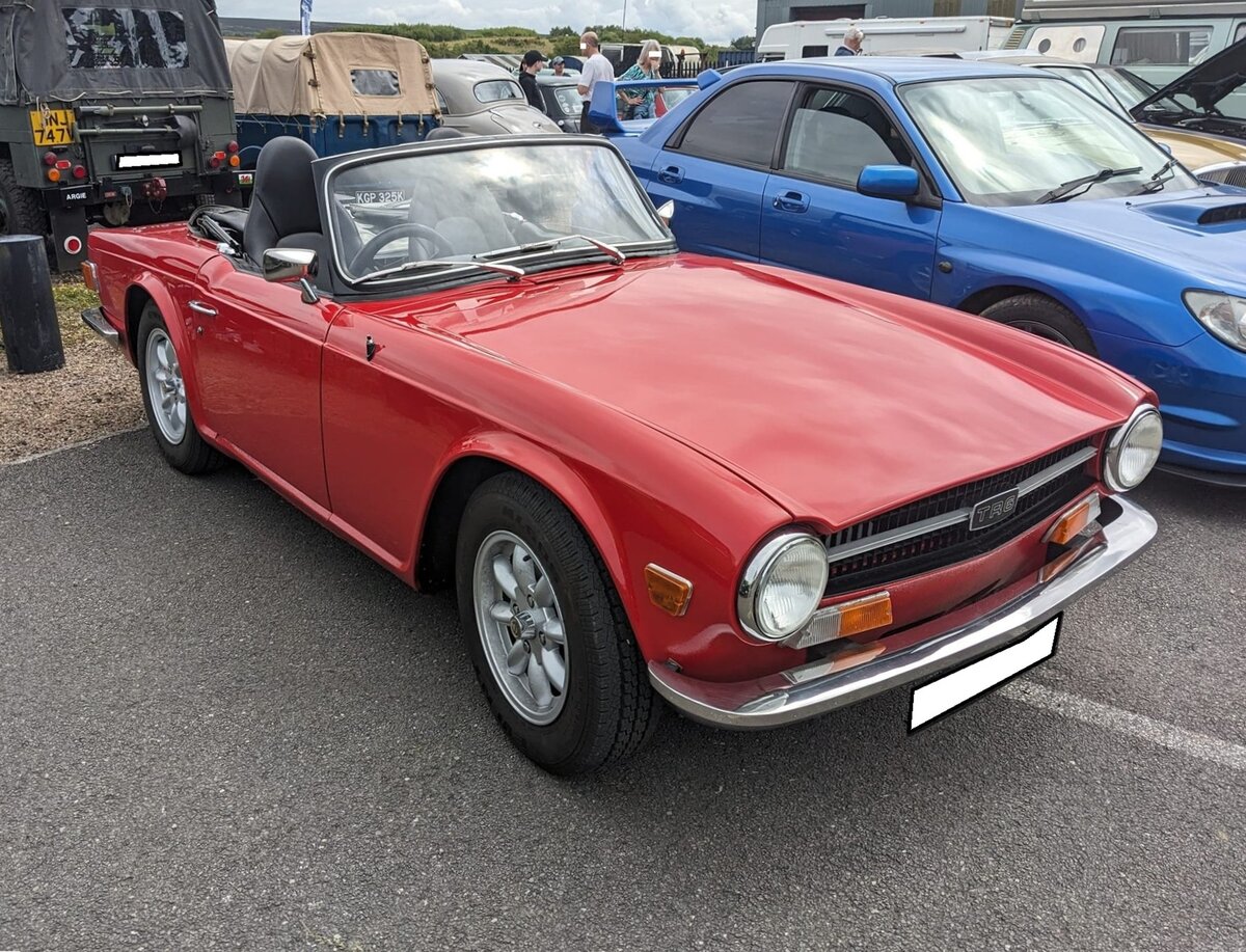 Triumph TR6 im Farbton signal red, produziert in den Jahren von 1970 bis 1976. Im Jahr 1970 erschien der letzte Abkömmling der klassischen Triumph TR-Baureihe in Form des TR6. Die Karosserie hatte der legendäre Italiener Giovanni Michelotti (*1921 +1980) gezeichnet. Der Sechszylinderreihenmotor des TR6 stammt vom Triumph 2000 und wurde auf 2498 cm³ Hubraum aufgebohrt. Dieser Motor leistet 150 PS und beschleunigt den TR6 auf eine Höchstgeschwindigkeit von 190 km/h. Der gezeigte TR6 wurde 1971 erstmalig zugelassen. Oldtimer meeting in Blaenavon/South Wales am 13.07.2024.