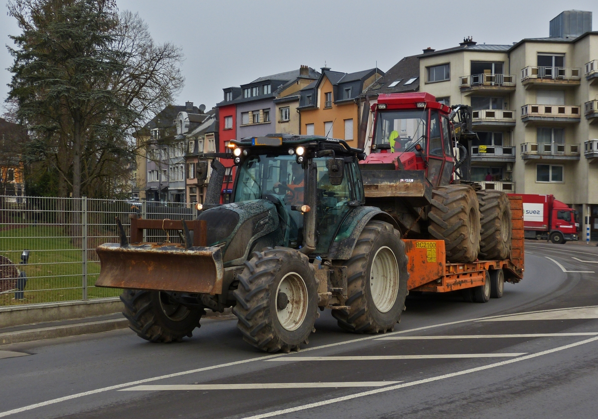 Valtra Traktor mit einem Holzrücker Traktor auf dem Hänger, gesehen in Ettelbrück. 02.2021