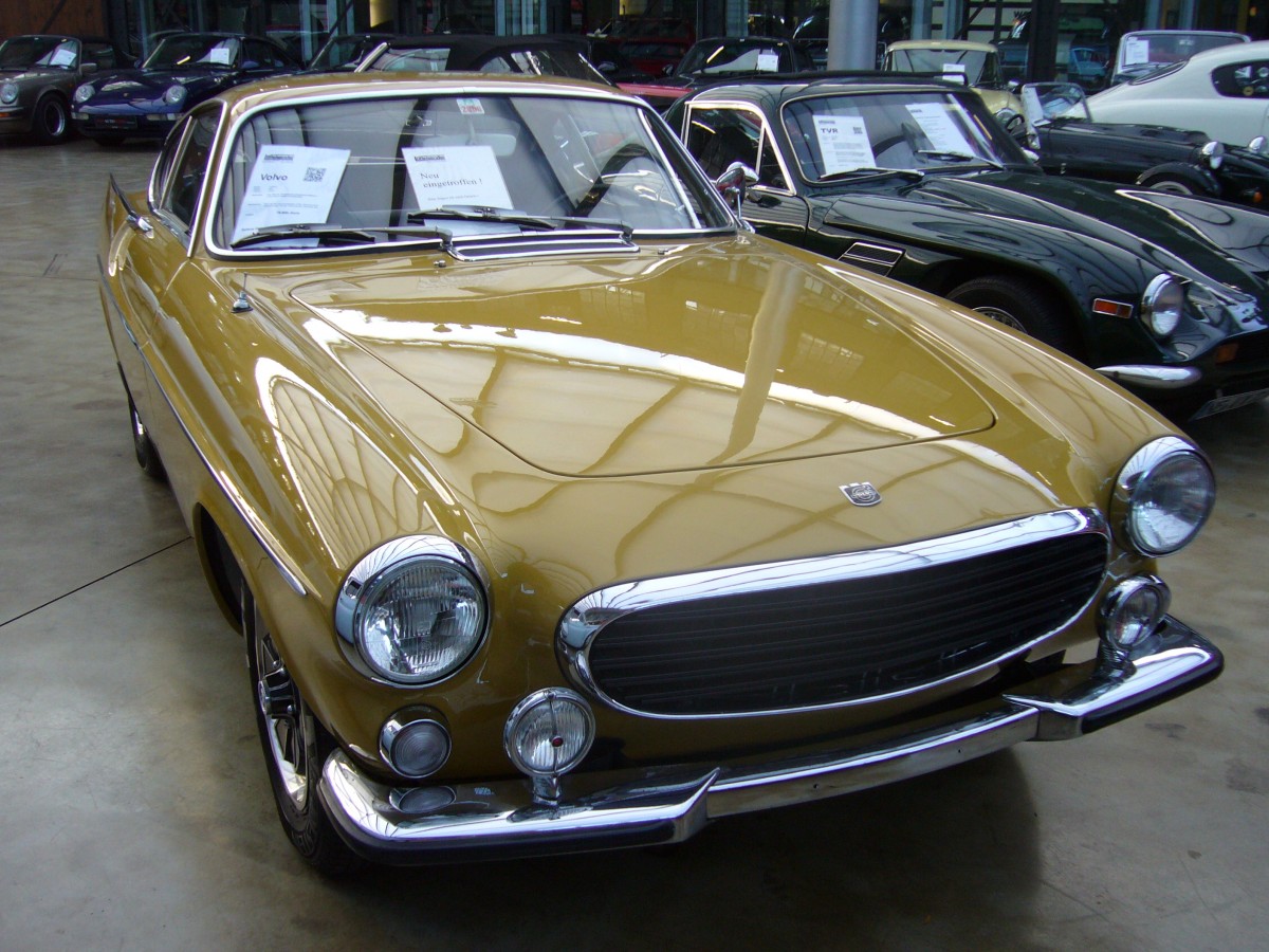 Volvo P 1800 E. 1969 - 1972. Der P 1800 E basiert auf dem bereits 1961 vorgestellten P 1800. Der Karosserieentwurf stammt von Frua/Turin. In den ersten beiden Jahren wurden die Wagen bei Jensen in GB zusammengebaut. Aufgrund von Qualitätsproblemen wurde die Produktion nach den Werksferien 1963 ins Volvo-Stammwerk Lundby/Göteborg verlegt. Alle dort produzierten P 1800 trugen auf der am Heck befestigten Typenplakette ein S für Schweden. In den letzten vier Produktionsjahren wurde der P 1800 mit einem 4-Zylinderreihenmotor mit Benzineinspritzung angetrieben, der aus 1986 cm³ Hubraum 124 PS leistet. Classic Remise Düsseldorf am 02.11.2014.