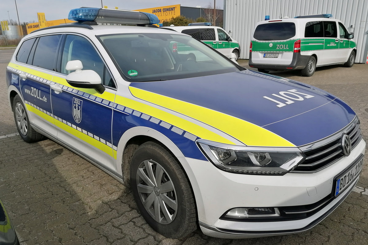 ZOLL-Einsatzfahrzeug VW-Passat in der aktuellen Farbgebung. Lübeck, März 2020.
Im Hintergrund  alte  grüne Einsatzwagen des Zolls.