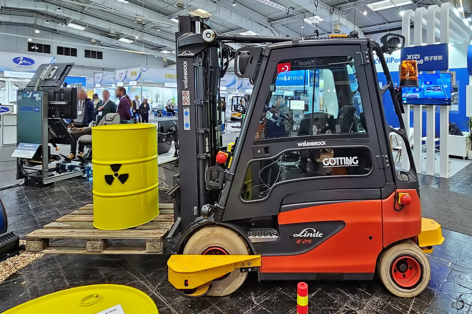 Dieser Linde E25 soll in Gefahrenbereichen zum Einsatz kommen und ist daher fernsteuerbar. Das Bedienpult ist links im Hintergrund zu sehen. (Messe Hannover, April 2024)