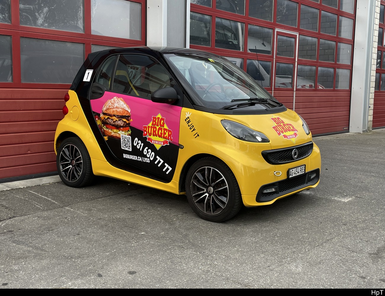 Gelb - Schwarzer Smart mit Werbung abgestellt in Worben vor einem Garage am 10.06.2023