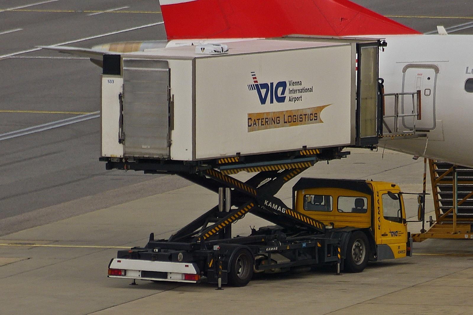 Kamag E-Catering Wiesel, mit angehobenen Container, um ein Flugzeug zu beliefern, gesehen auf dem Flughafen von Wien. 06.2023