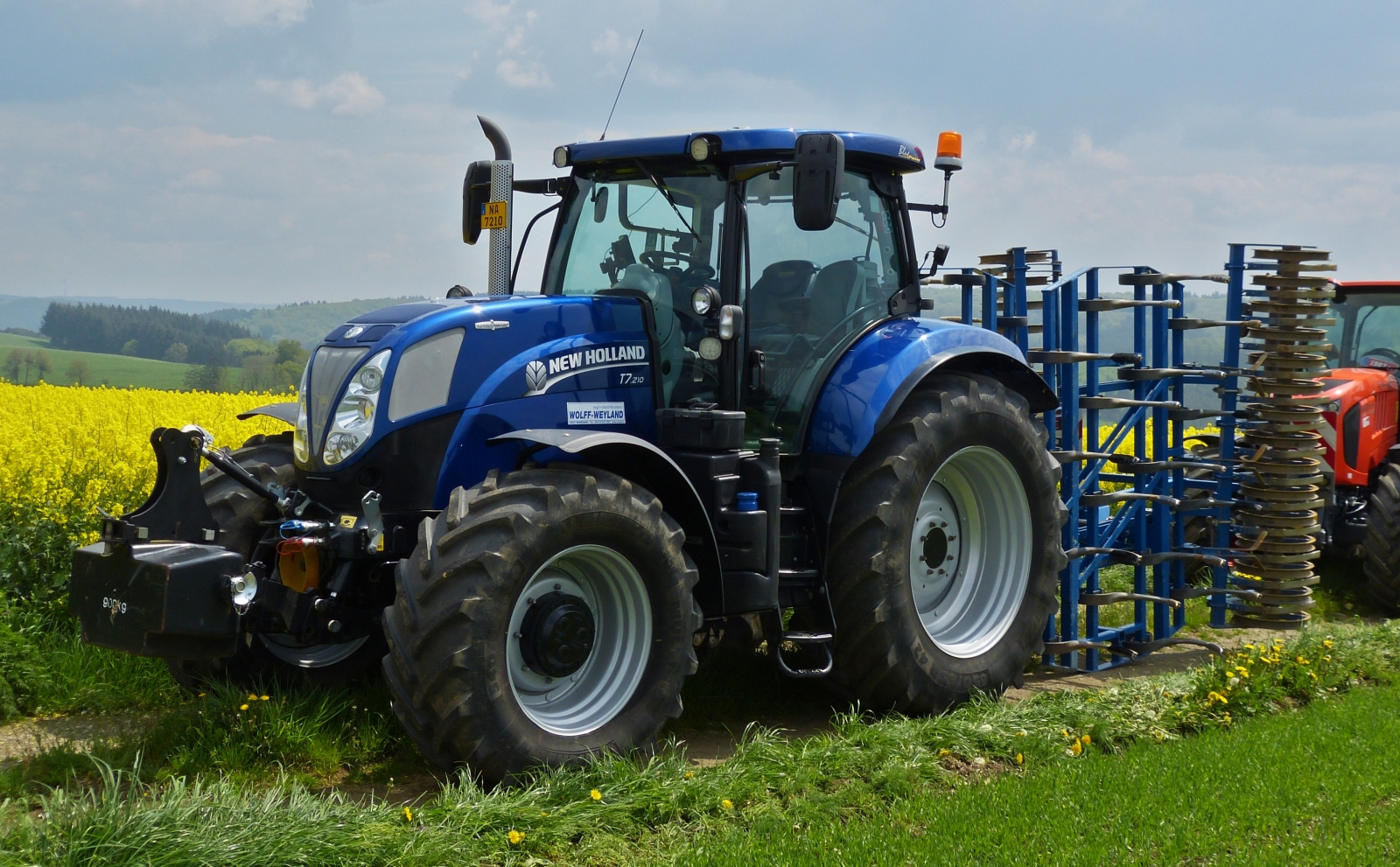 New Holland T7.210 Traktor mit Bodenlockerungsmaschine steht bereit um an der Rundfahrt durch Brachtenbach beim „Baurefest zu Brotebach“ mitzufahren. 14.05.2023 