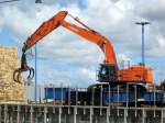Hitachi Zaxis 670 LC Kettenbagger ist am 14.06.2014 beim  Löschen  eines mit Holz beladenen Kümo's im Hafen von Wismar.