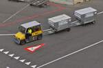 Kleiner Schlepper unterwegs mit 2 Koffercontainer auf dem Flughafen von Wien.